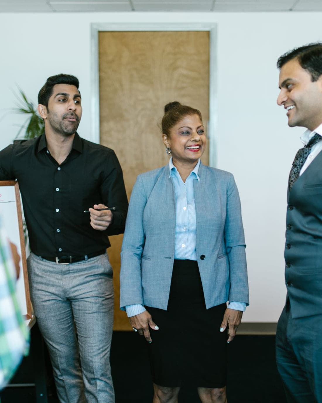 Three colleagues standing and talking together in an office.