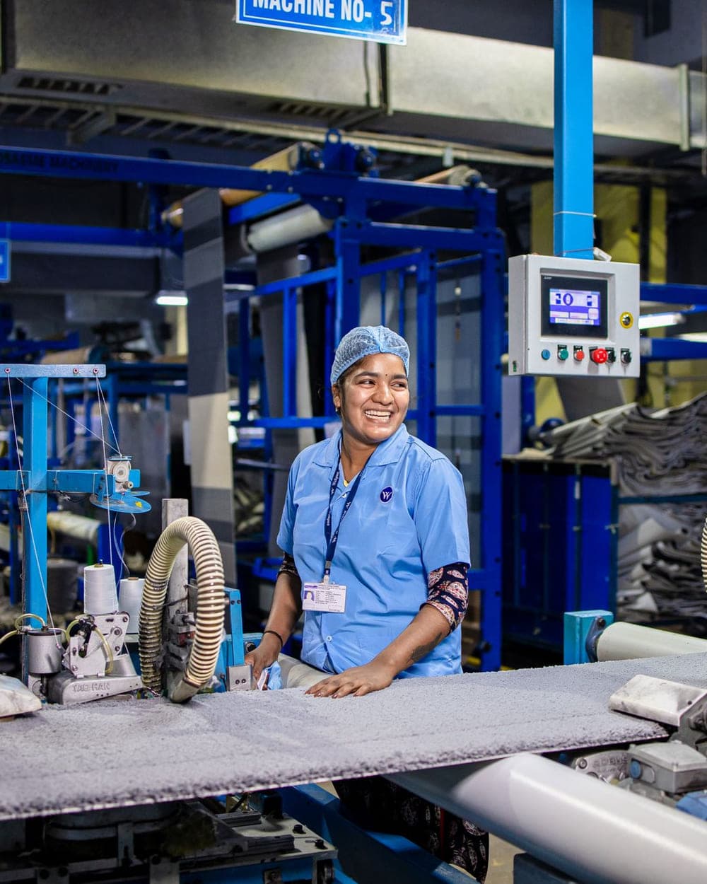 A machine operator at her station on the floor of a manufacturing unit.